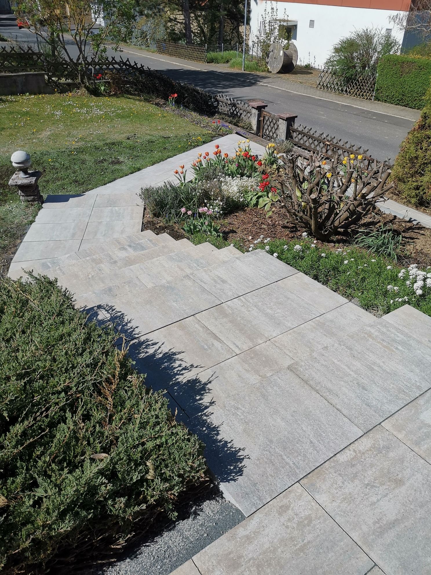 Steinstufen führen zu einem Haus mit einem kleinen, von Büschen gesäumten Blumenbeet.