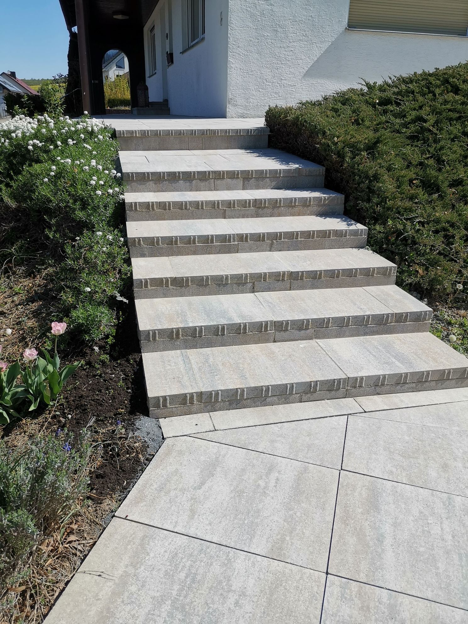 Steinstufen führen zu einem weißen Gebäude mit Landschaftsgestaltung auf beiden Seiten.