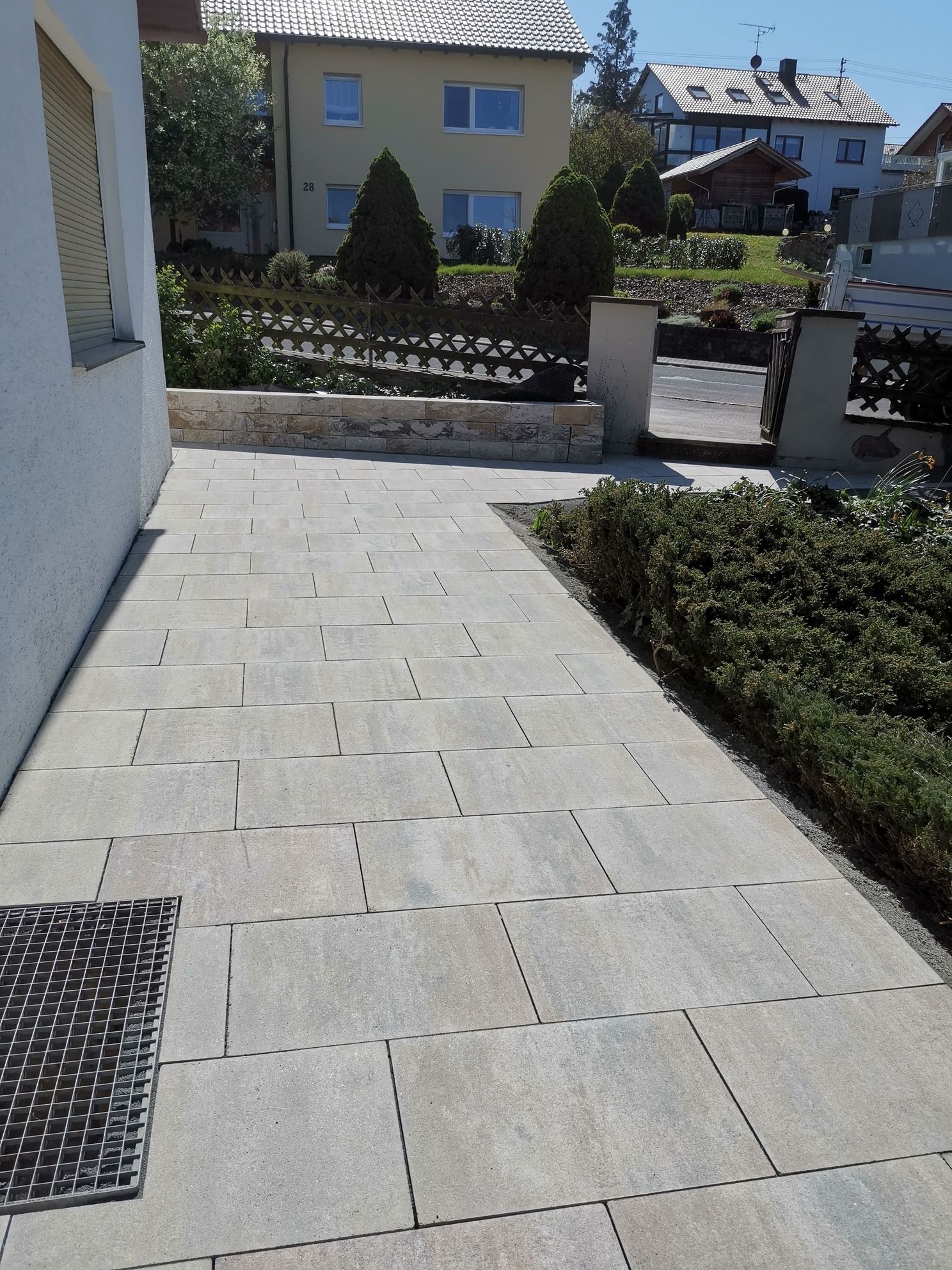 An einem sonnigen Tag führt ein Steinweg zu einem Garten und Häusern.