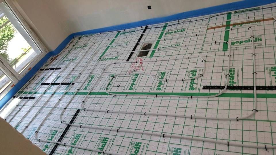 Mur isolé avec tuyauterie intégrée, probablement pour chauffage radiant. Éléments blancs, verts et noirs.