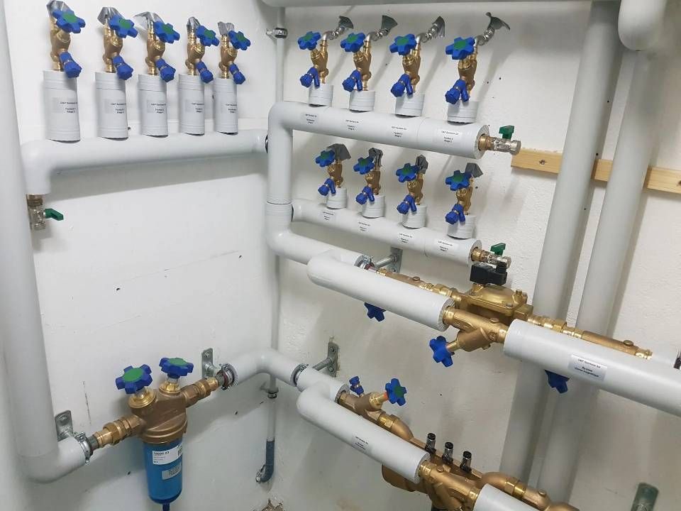 Tuyaux avec vannes bleues et vertes sur un mur ; système de distribution d'eau.