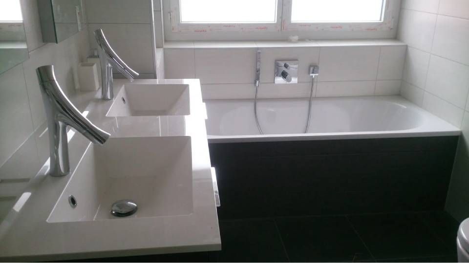 Salle de bains moderne avec deux lavabos, une baignoire et une fenêtre. Décoration en noir et blanc.