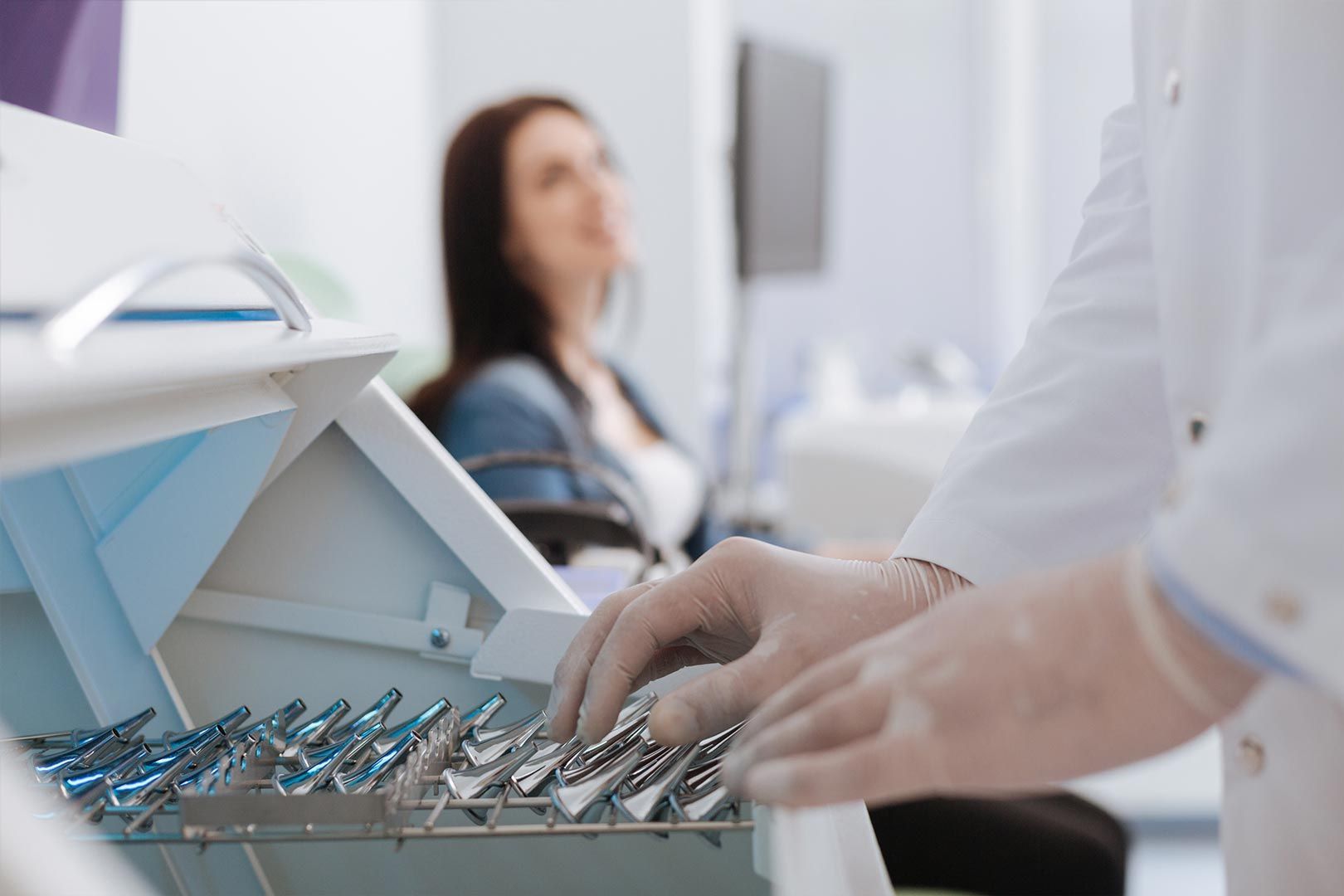 Un dentista sostiene una caja de instrumentos dentales frente a un paciente.