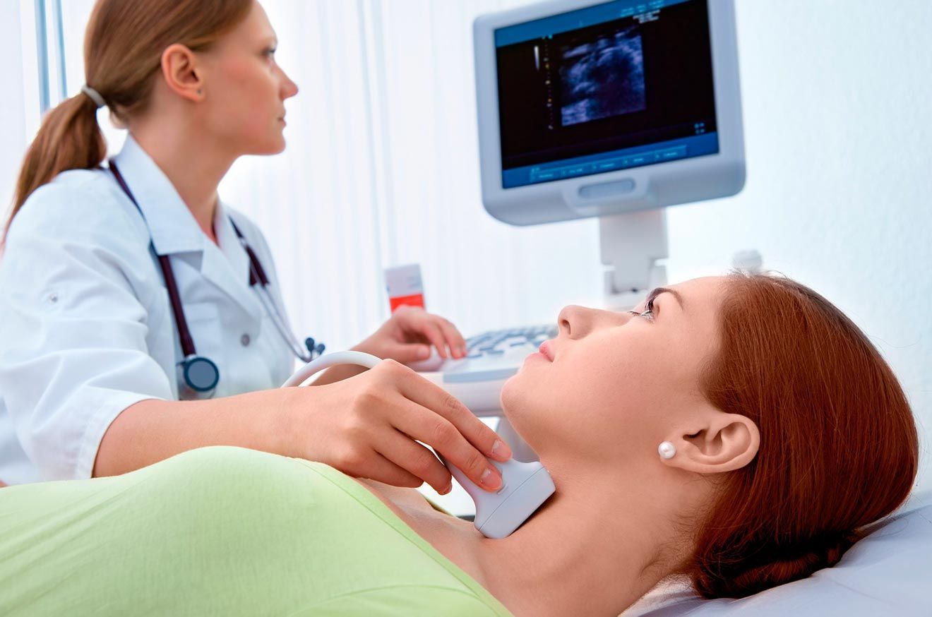 A una mujer le están haciendo una ecografía del cuello por parte de un médico.