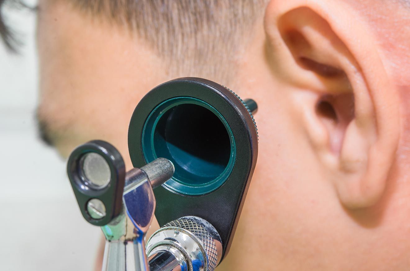 Un hombre se está haciendo examinar el oído por un médico.