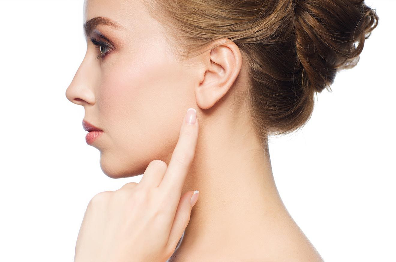 Una mujer se toca la oreja con el dedo.