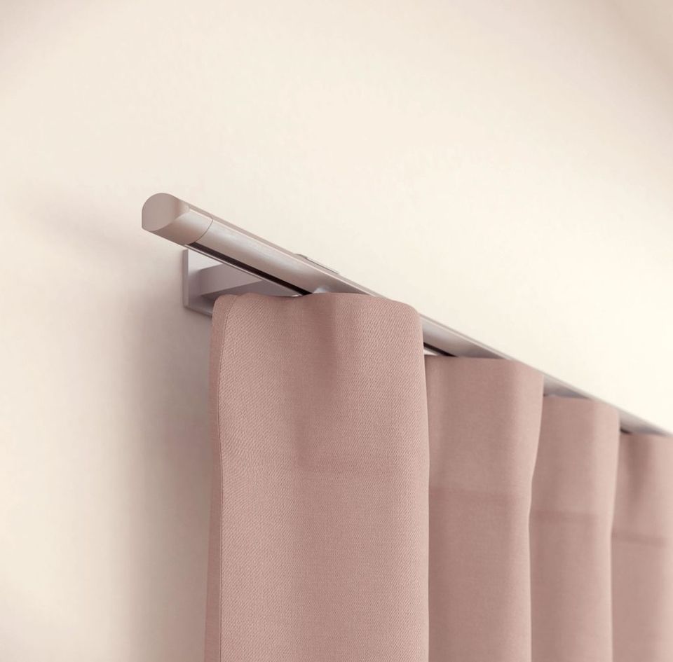An einer weissen Wand hängt ein rosa Vorhang.