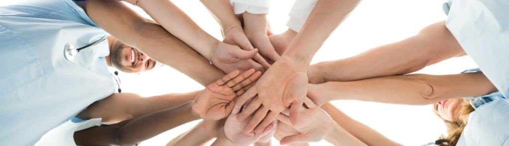 Eine Gruppe von Leuten legt ihre Hände zu einem Kreis zusammen.