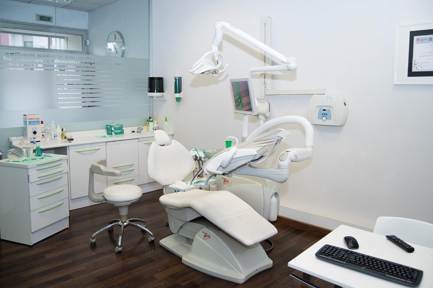 Consultorio dental moderno con sillón, instrumental, lavabo y armarios.