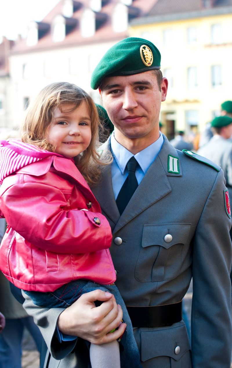 ein Mann in Militäruniform hält ein kleines Mädchen