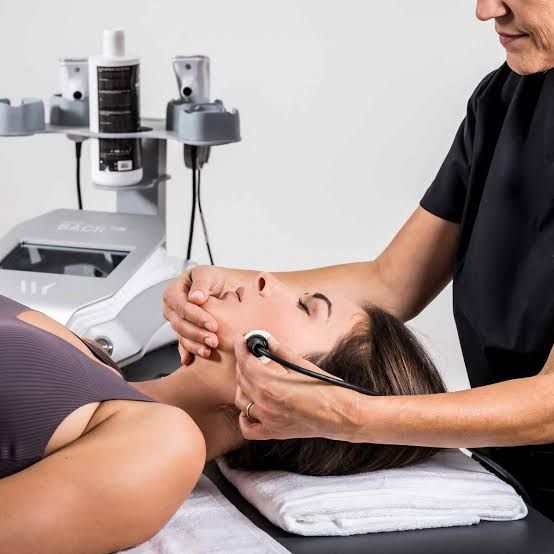 Une femme se faisant masser la peau à l'aide d'une machine.