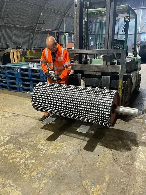 Un hombre está trabajando en un rodillo grande en una fábrica.