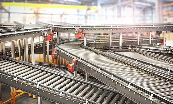 Una cinta transportadora en una fábrica con muchos rodillos sobre ella.