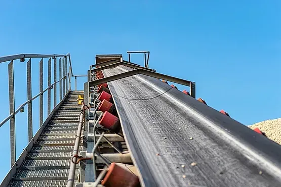 Una cinta transportadora con escaleras que conducen a ella en una fábrica.
