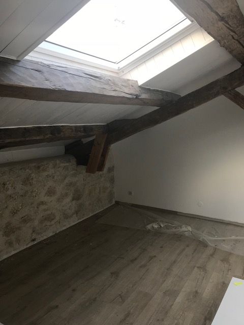 Chambre sous combles avec mur blanc.