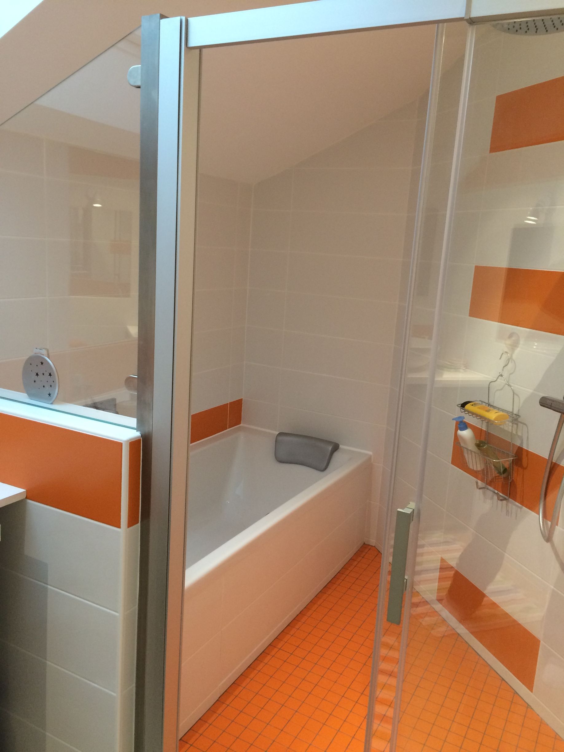 Salle de bains avec carrelage clair et orange.