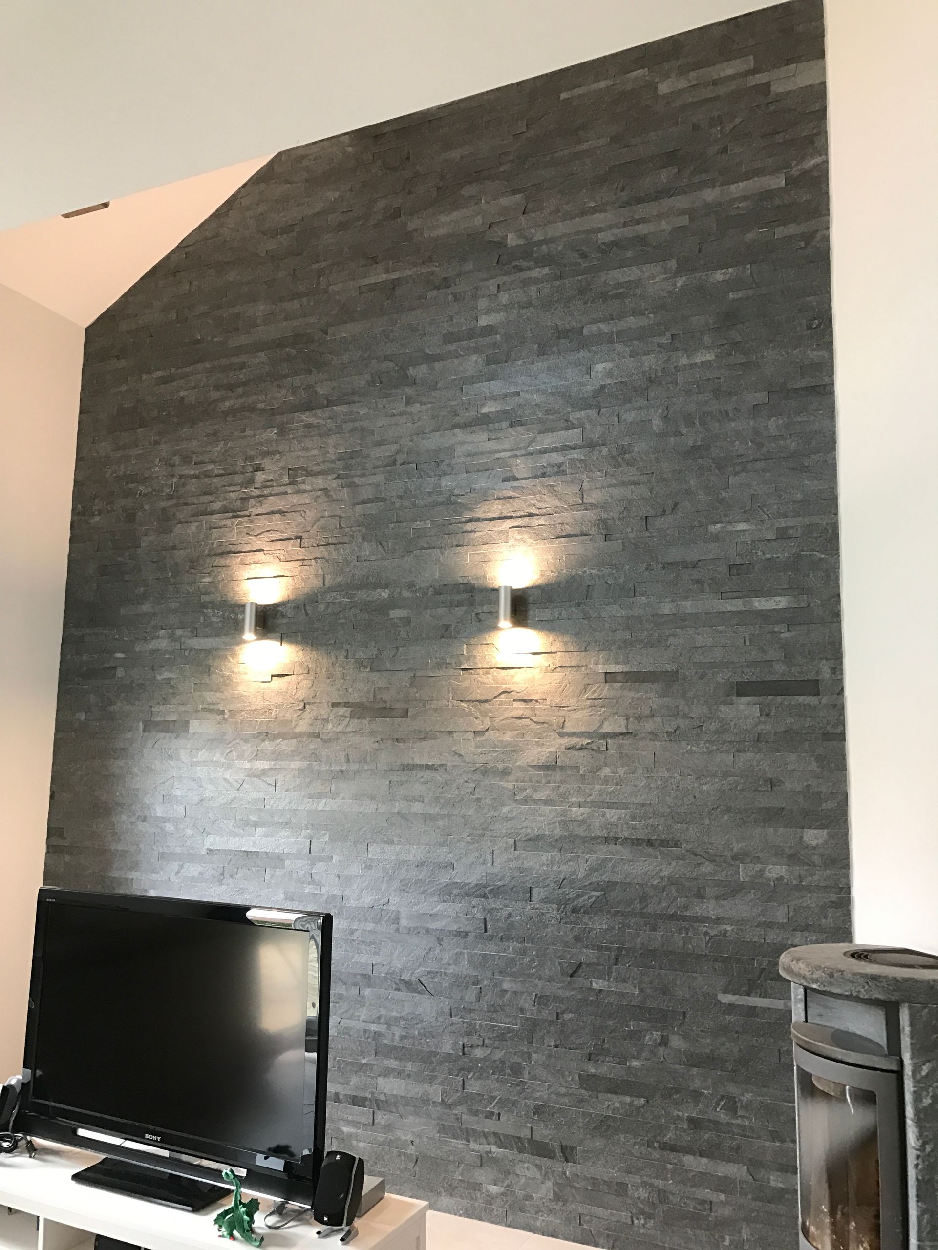 Pièce avec un mur possédant partiellement de la tapisserie effet briquettes grises.