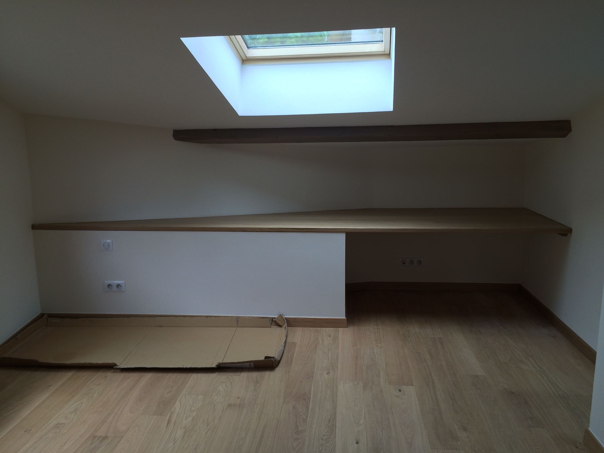 Pièce sous des combles possédant un parquet en bois.