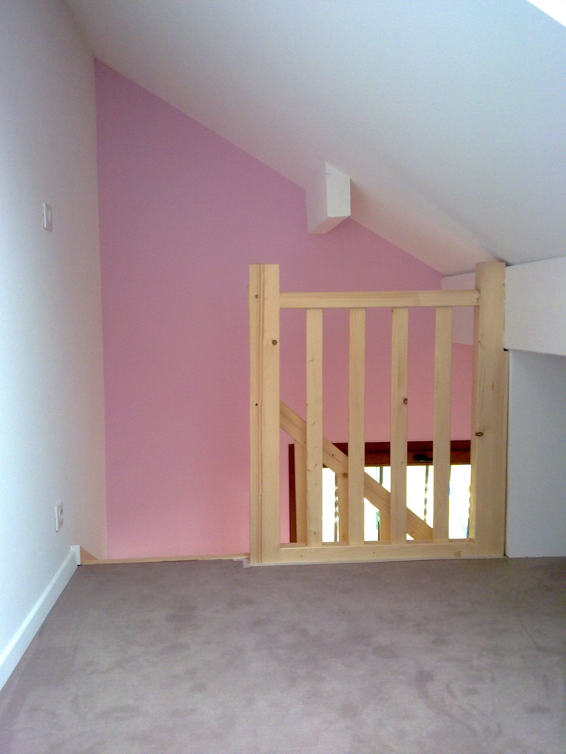 Rambarde en bois d'un escalier avec un mur rose.