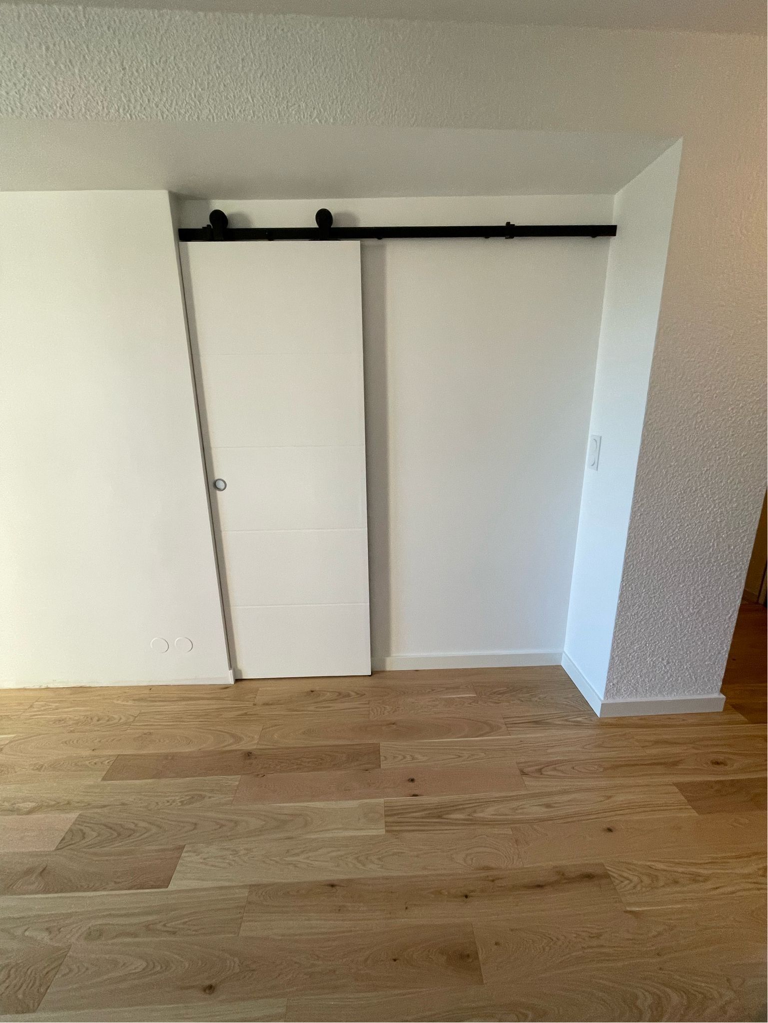 Mur blanc avec sol en parquet.