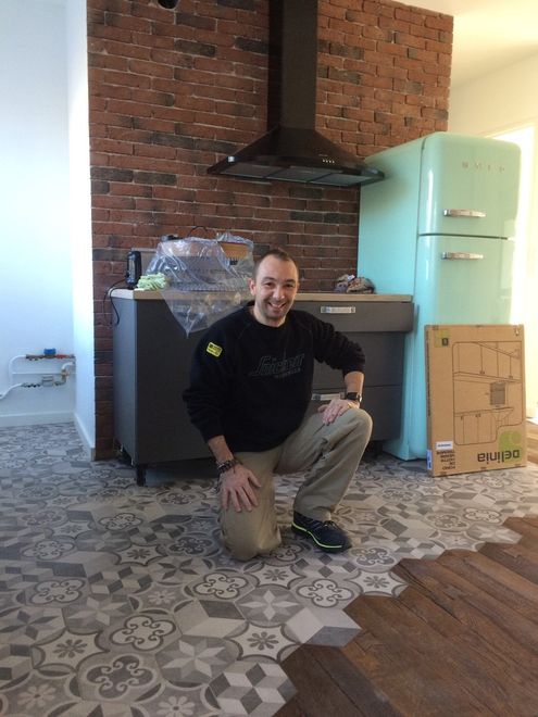 Monsieur Briche qui pose devant une cuisine rénovée.