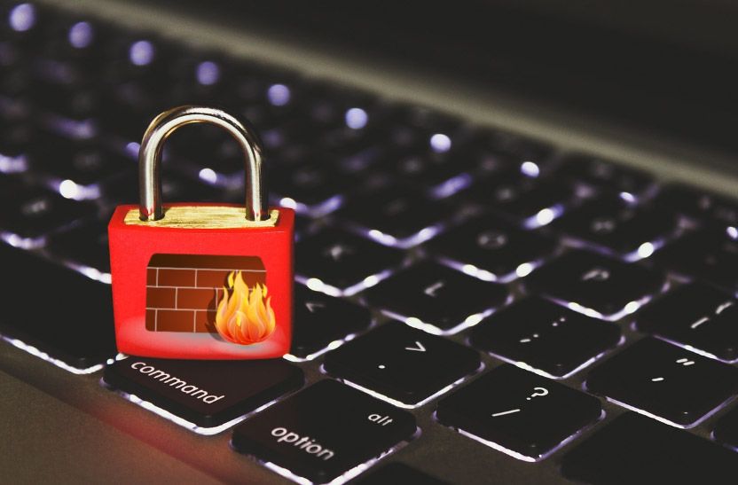 Un candado rojo con el símbolo de un cortafuegos en el teclado de un ordenador portátil simboliza la seguridad de la red.