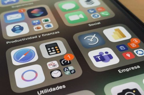Primer plano de la pantalla de un teléfono inteligente que muestra iconos de aplicaciones categorizados en carpetas etiquetadas como “Productividad y finanzas”, “Social”, “Empresa” y “Utilidades”.