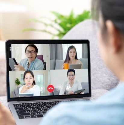 Persona en videollamada con otras cuatro personas en un ordenador portátil, en interiores.