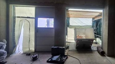 Modernes Ladenlokal im Bau mit Holzregalen, Glasfront und heller Deckenbeleuchtung
