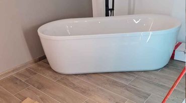 Modernes Badezimmer mit Glasdusche, schwebendem Waschtisch aus Holz, weißer Badewanne und grauem Teppich