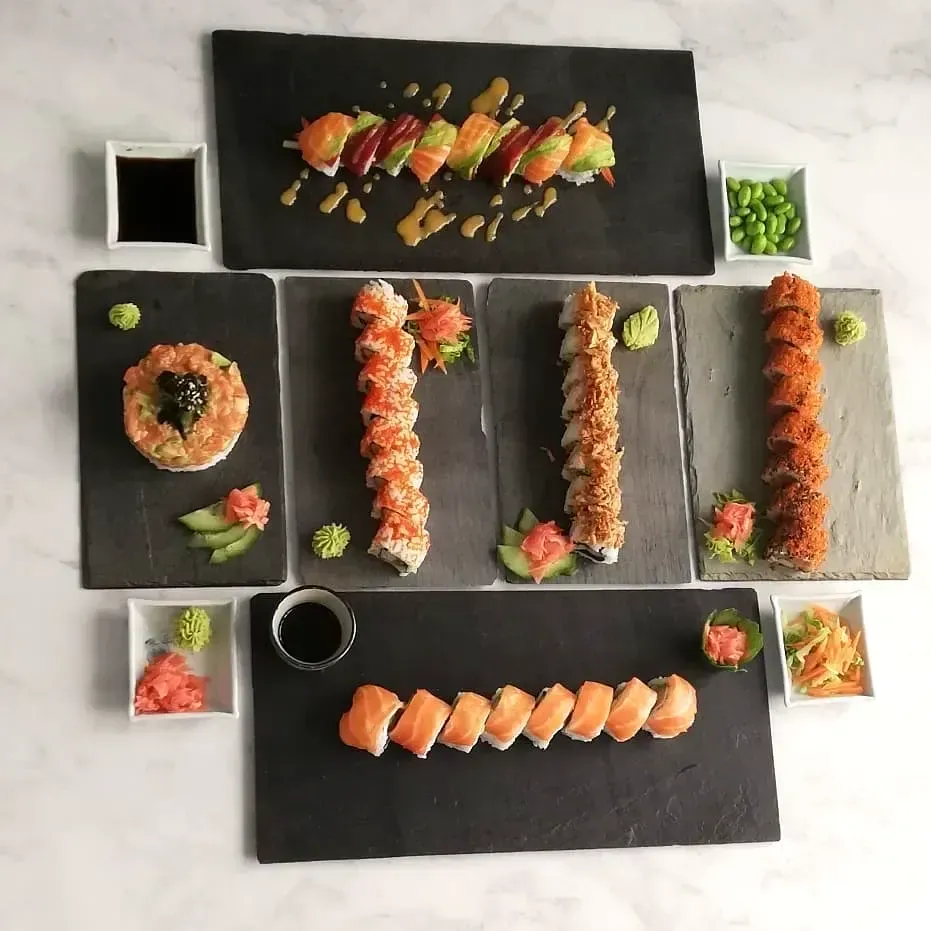 Surtido de sushi en platos negros, con rollos y nigiri dispuestos de forma ordenada.