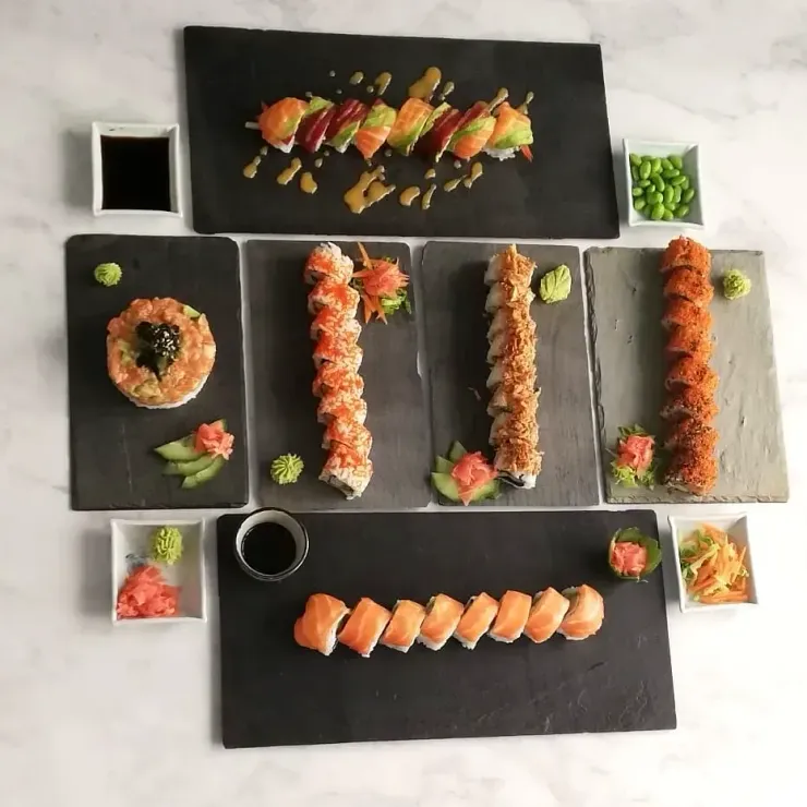 Surtido de sushi en platos negros, con rollos y nigiri dispuestos de forma ordenada.