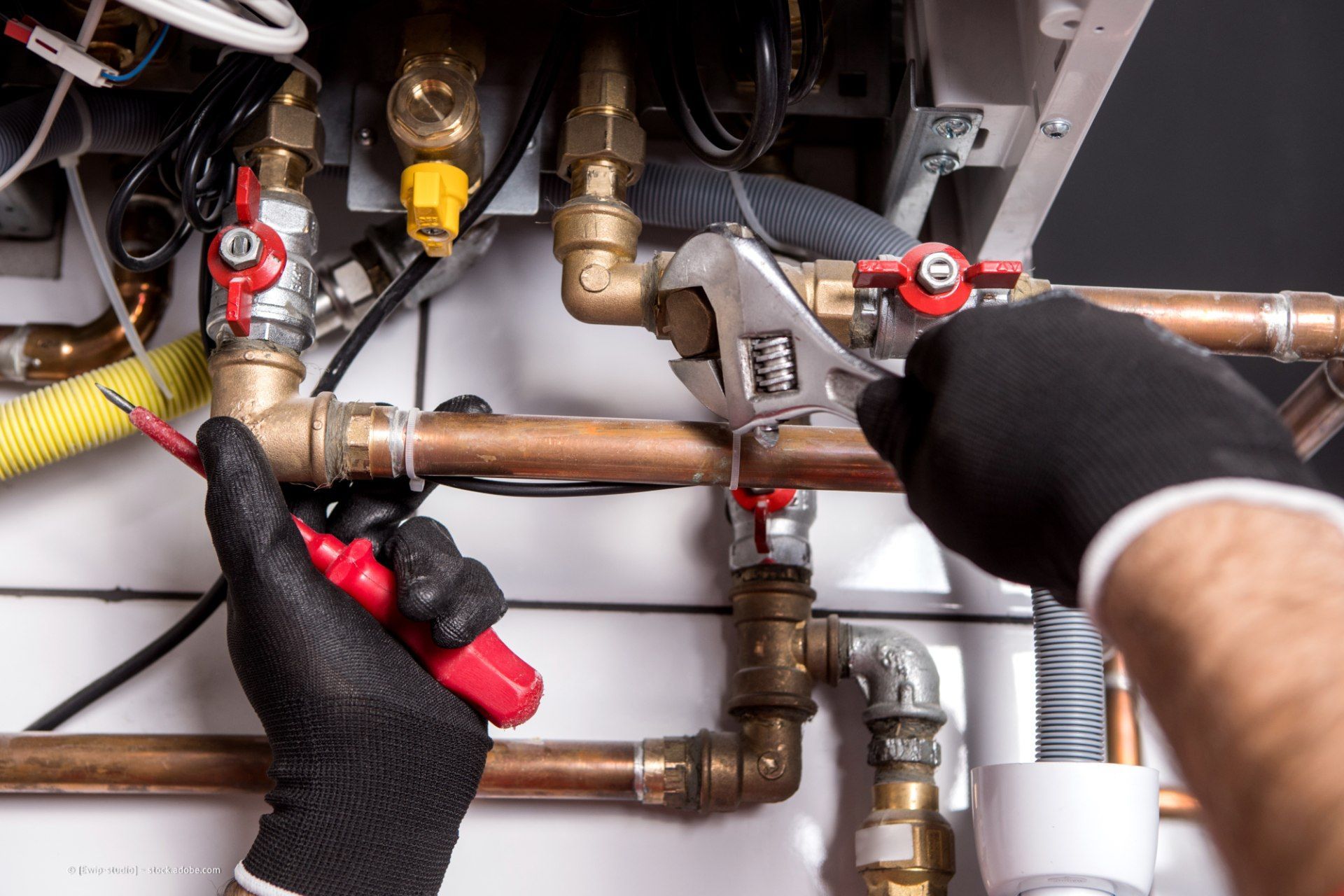 Klempner schraubt an Rohren