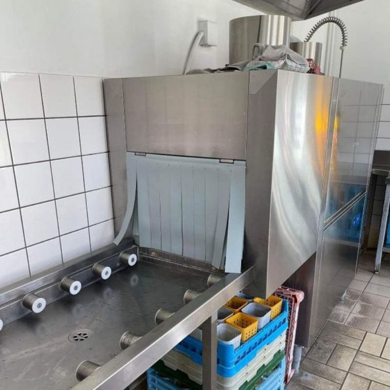 Lave-vaisselle professionnel en cuisine. En acier inoxydable, avec roulettes et rideaux.