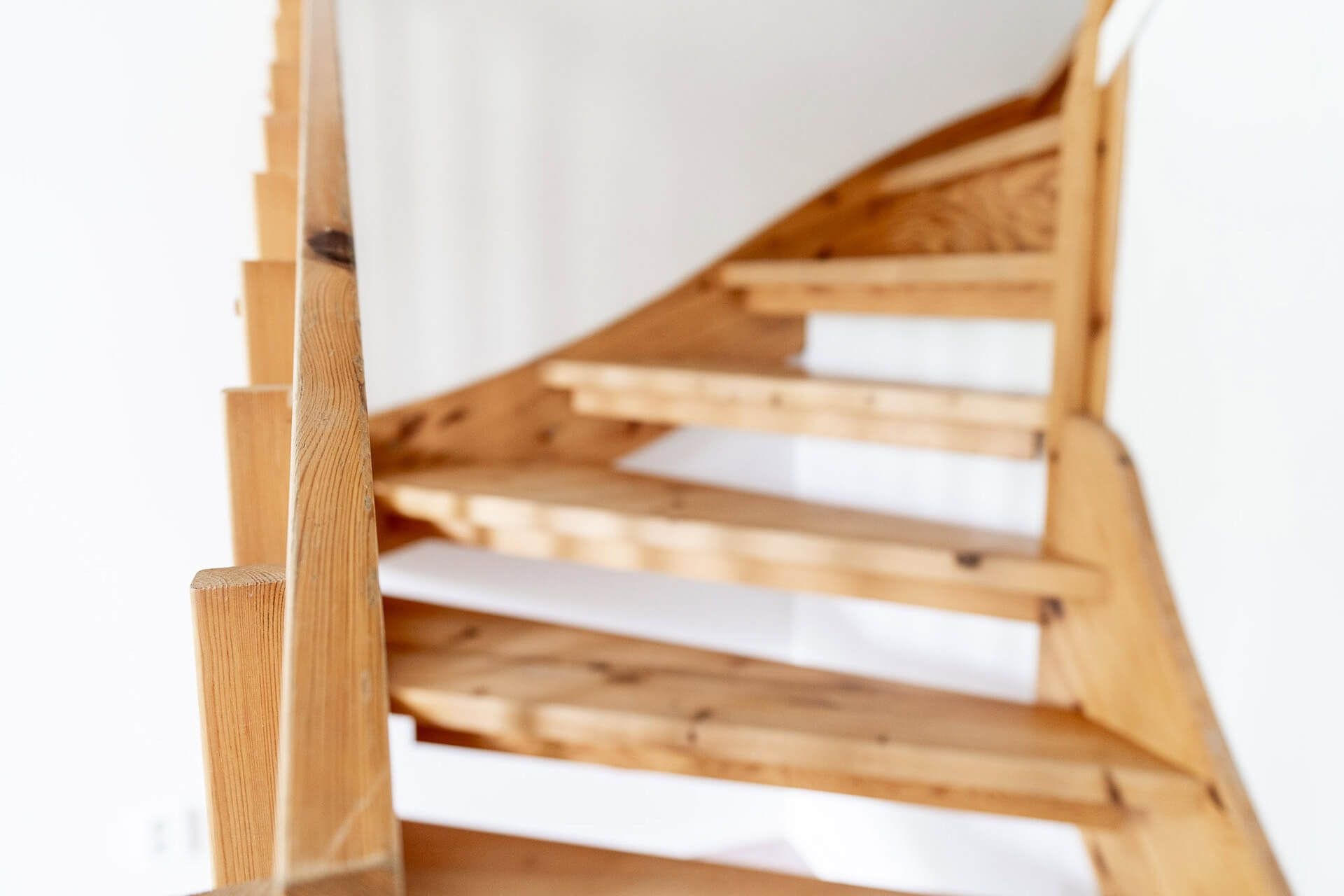 Puiset kierreportaat valkoista seinää vasten.