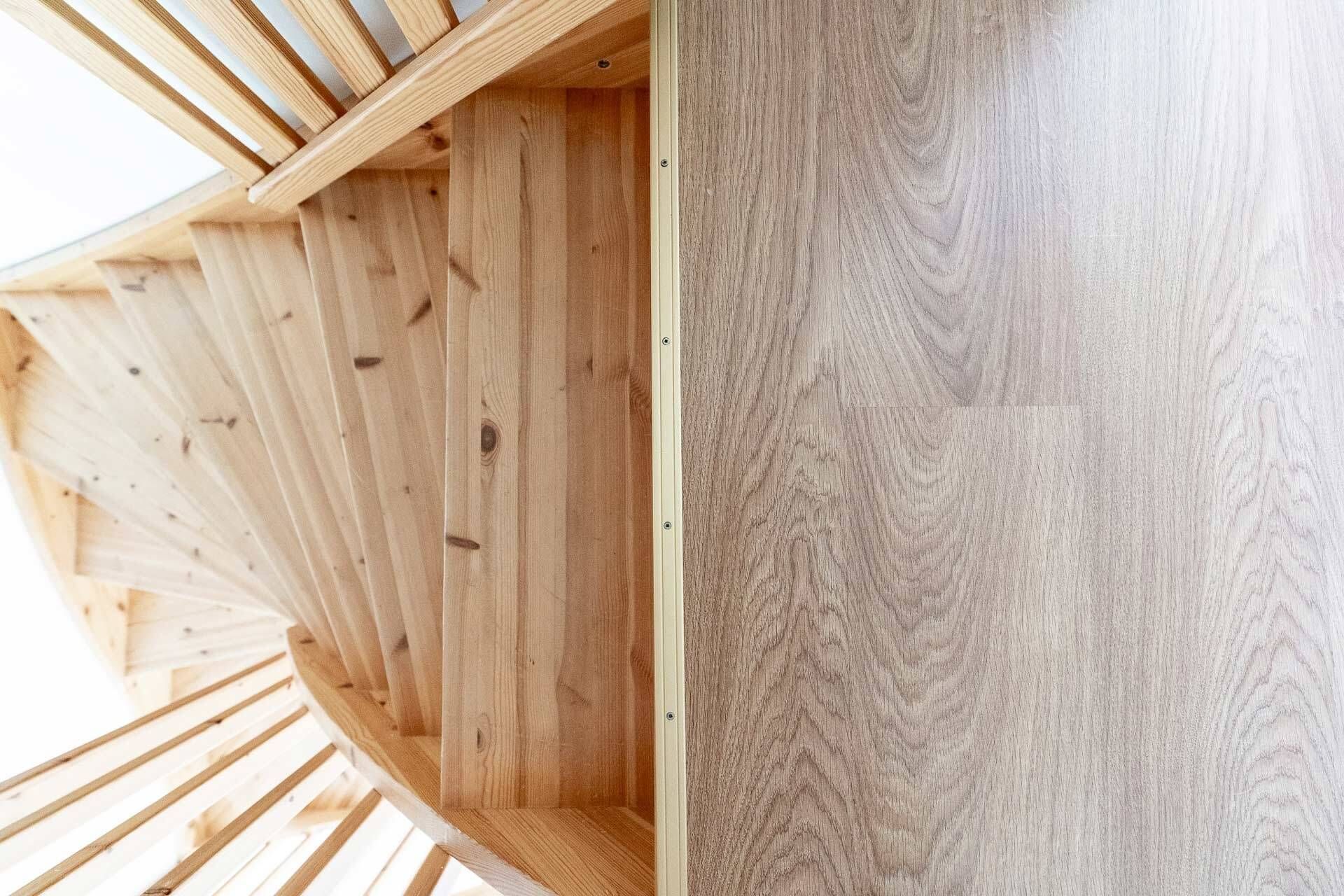 Puinen kierreportasto puulankkulattian vieressä ylhäältä katsottuna.