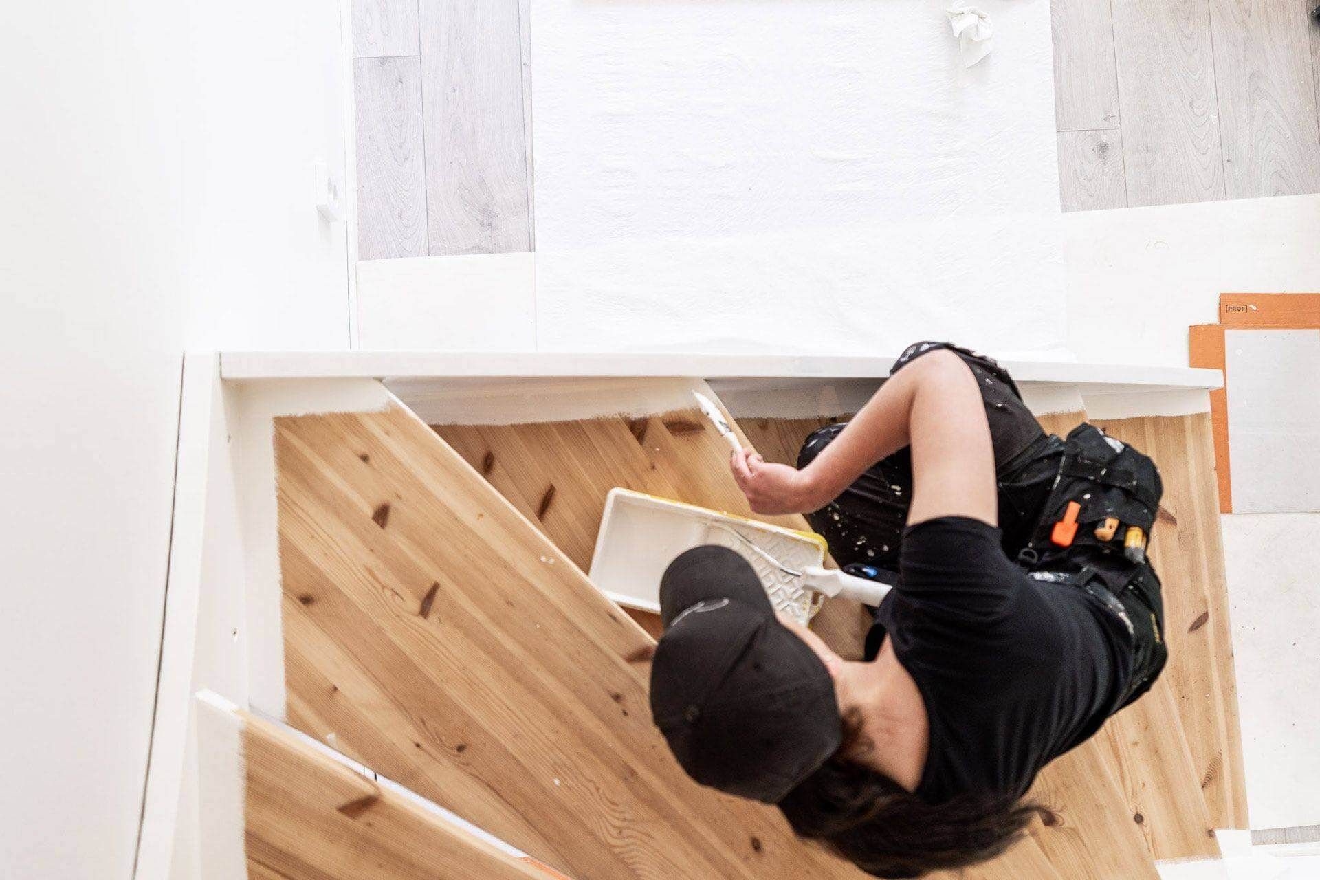 Henkilö työskentelee puisilla portailla työkaluja kädessään.