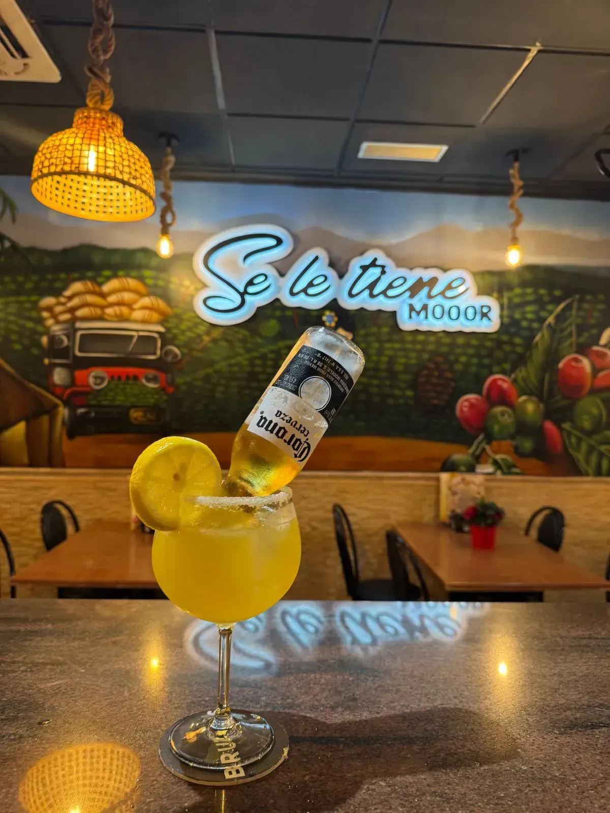 Una margarita amarilla con una botella de cerveza Corona boca abajo, adornada con una rodaja de limón