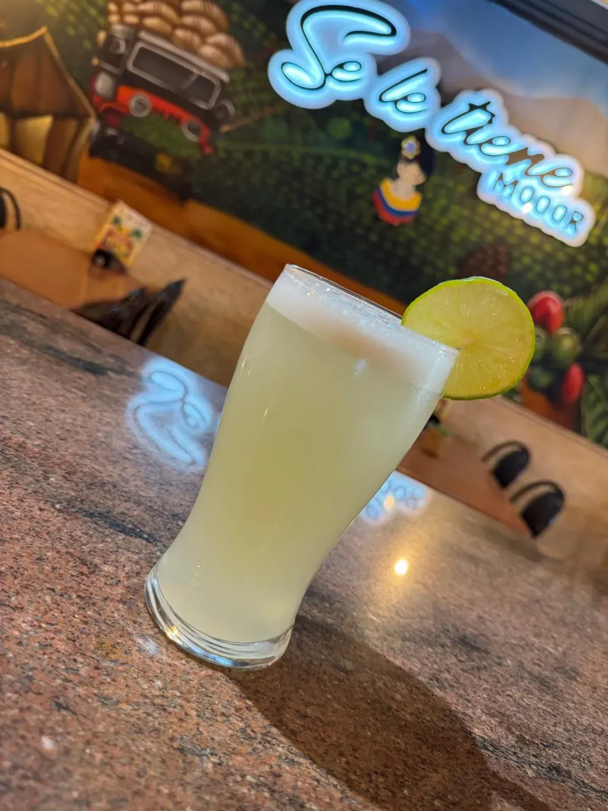 Un vaso de limonada de color amarillo claro bien fría, adornado con una rodaja de lima