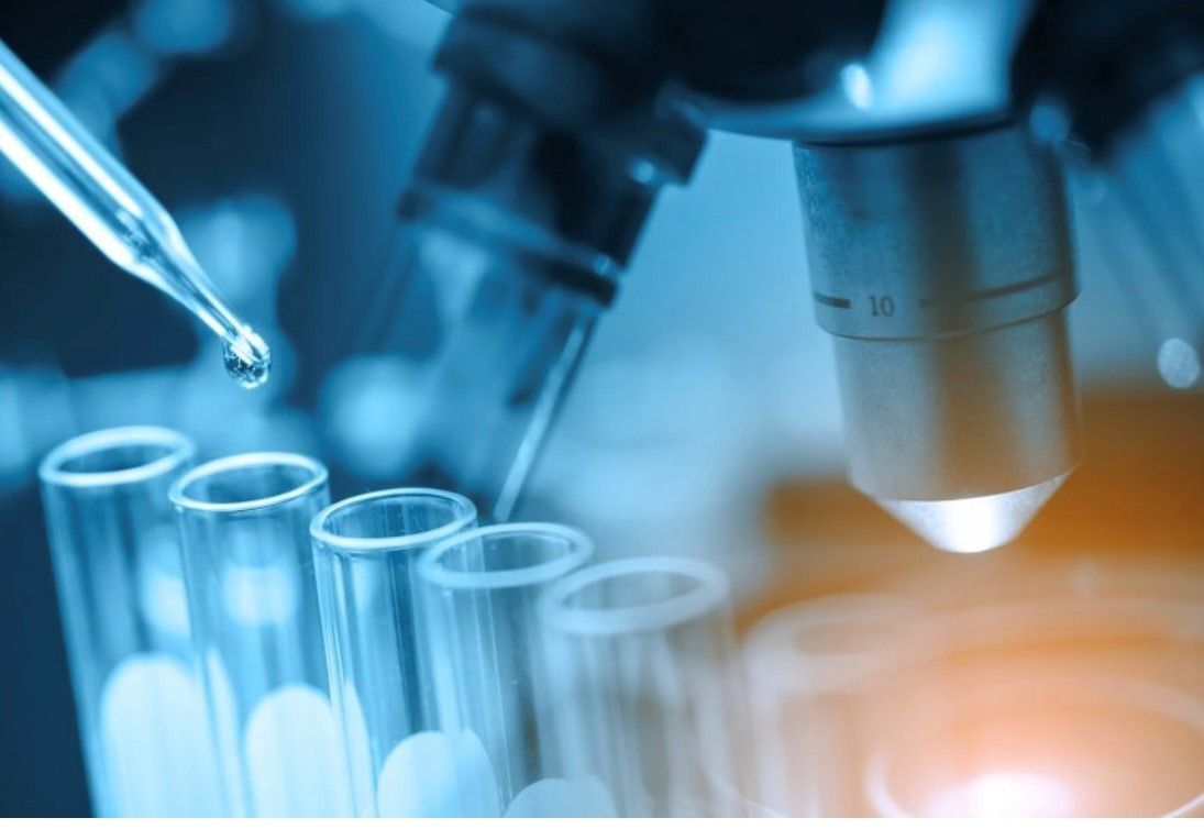 Mikroskop und Reagenzgläser in einem Labor, mit einer Pipette zum Abfüllen von Flüssigkeit.