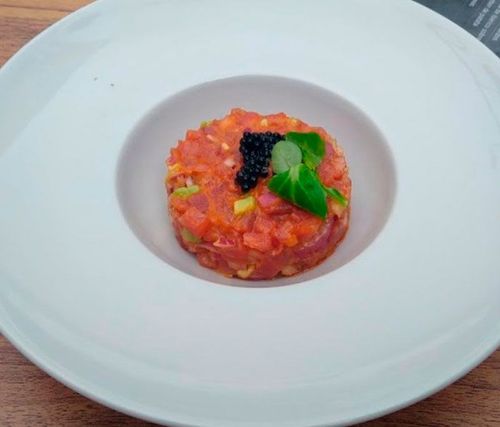 Un plato blanco cubierto con salsa de tomate y caviar.