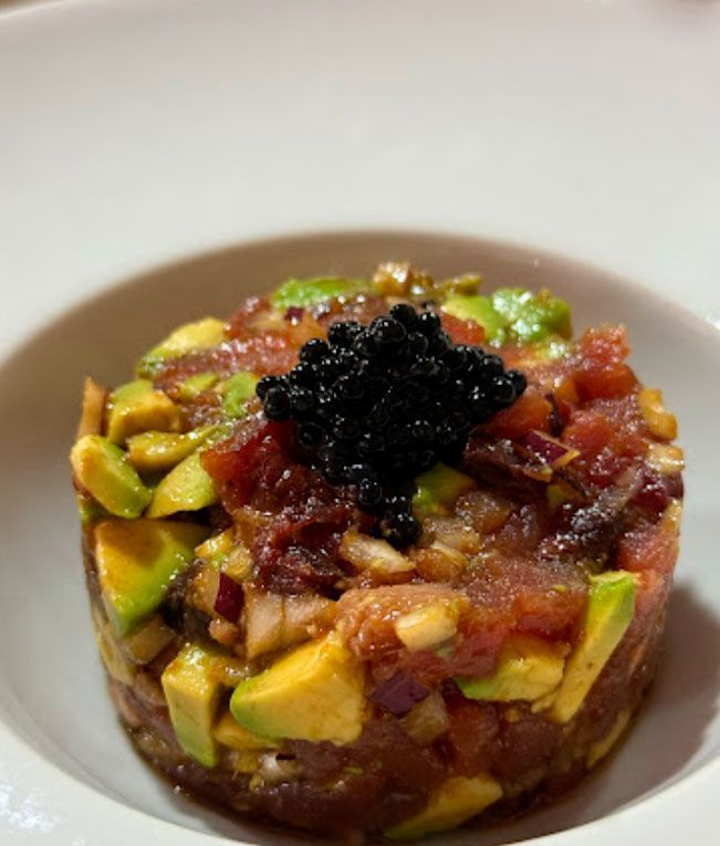 Un plato de comida con aguacate y caviar encima.