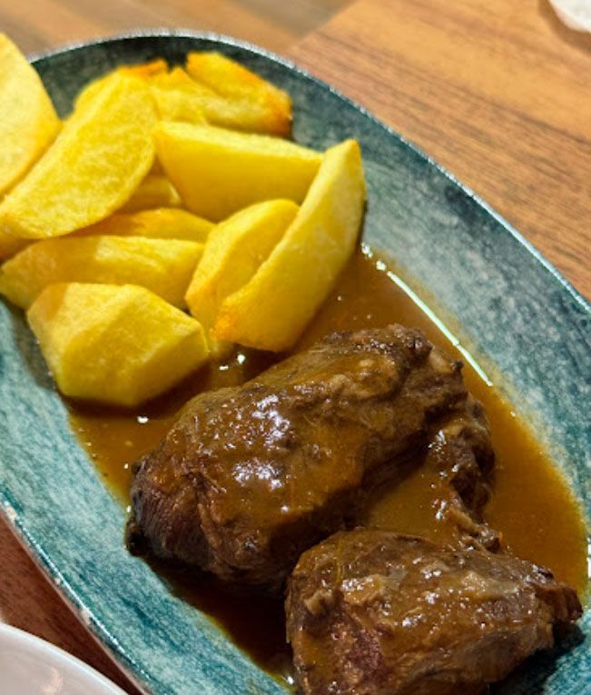 Un plato de comida con carne y patatas en una mesa.