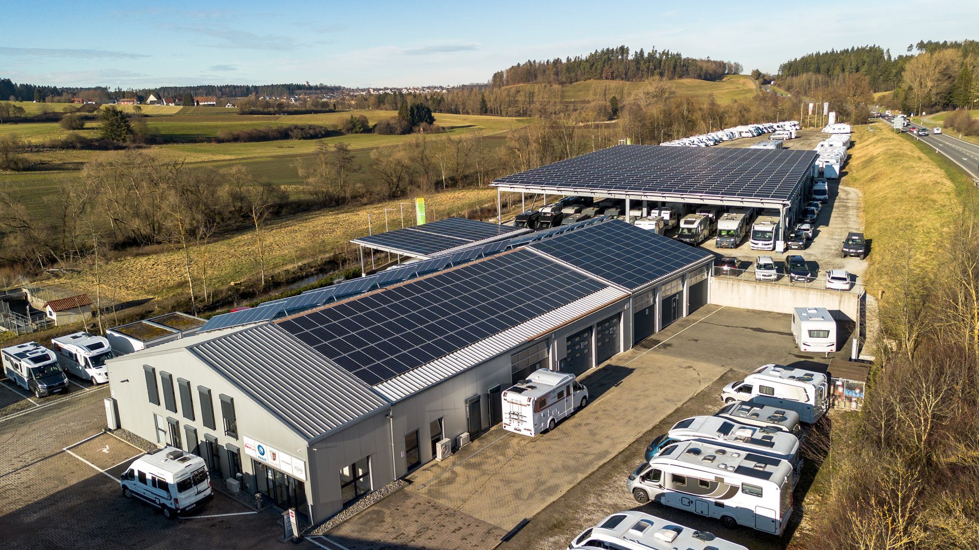 Wohnmobilhändler mit Solarpaneelen auf dem Dach und draußen geparkten Wohnmobilen.
