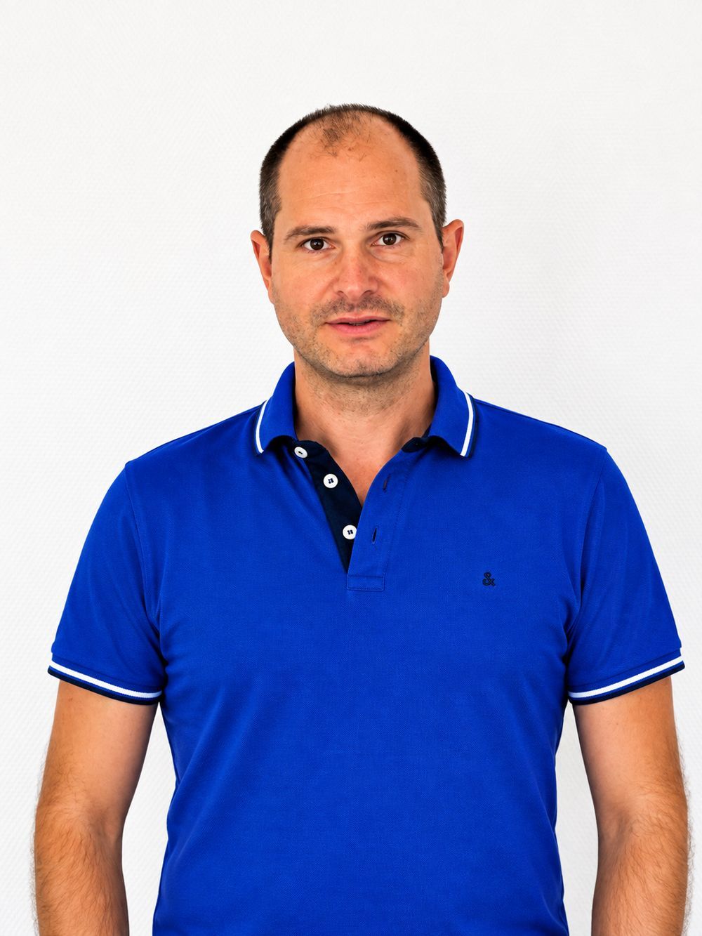 Mann in einem blauen Poloshirt vor weißem Hintergrund