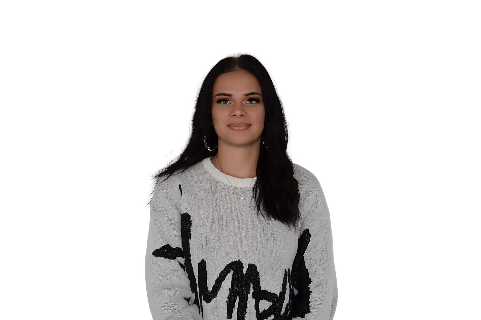 Frau mit langen dunklen Haaren, die einen grauen, flauschigen Pullover mit schwarzer Aufschrift trägt, lächelt in die Kamera.