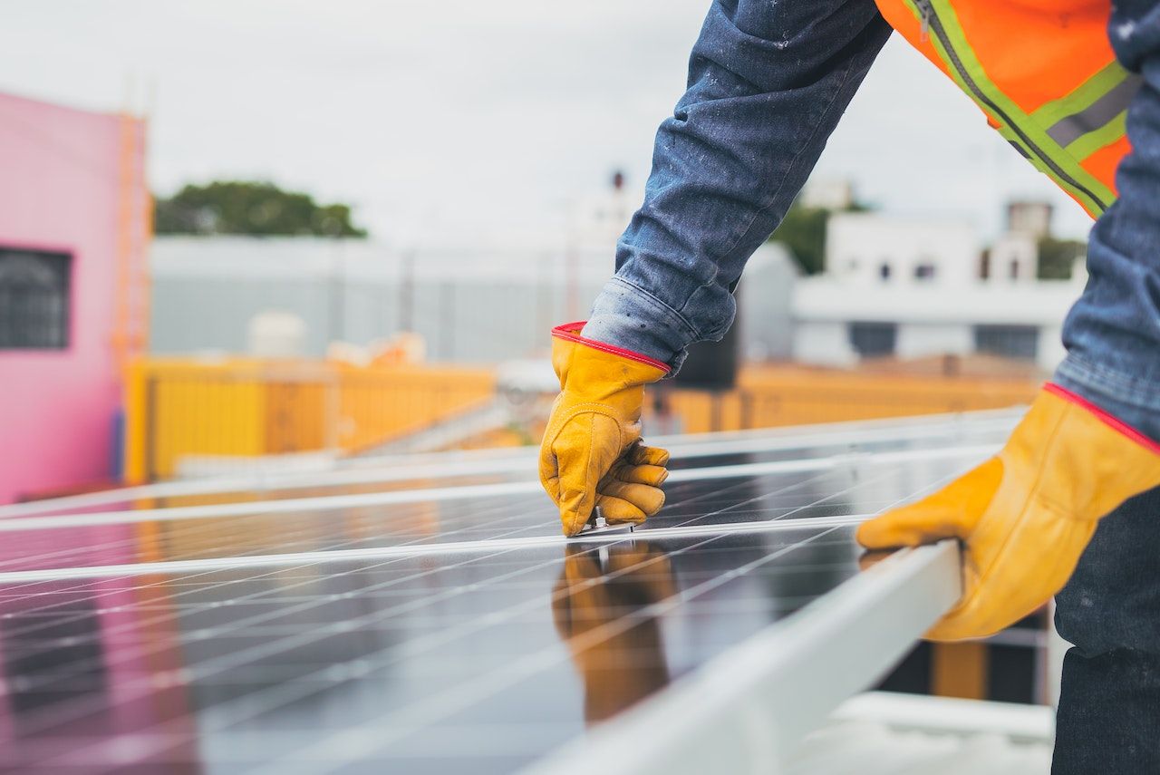 Un hombre está instalando paneles solares en un tejado.