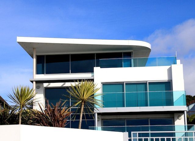 Una casa moderna con balcón y palmeras al frente.