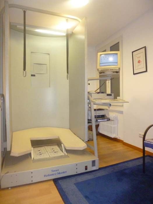 Habitación de paciente con escáner de imágenes, monitor y alfombra azul en un entorno clínico.