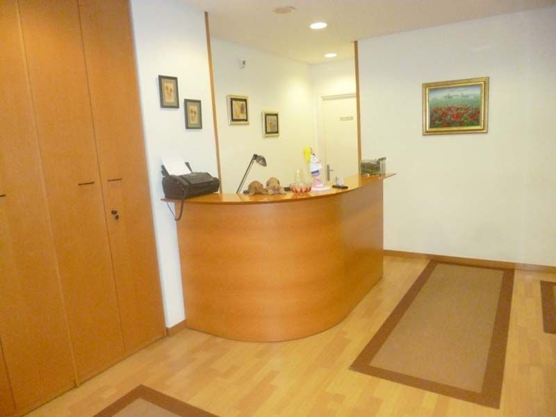 Mostrador de recepción con mostrador curvo de madera, obras de arte en la pared y suelo de madera clara.